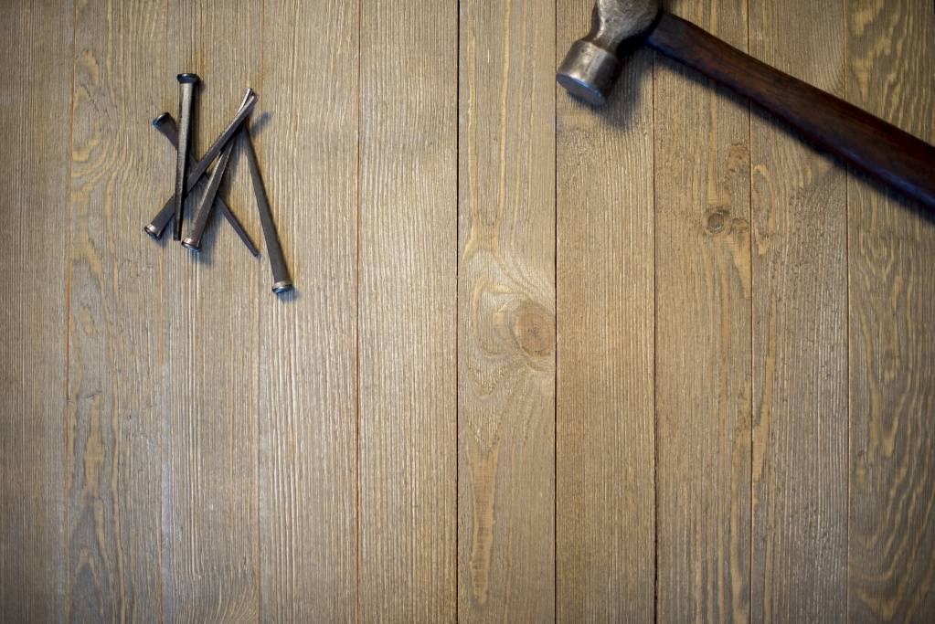 overhead-shot-hammer-nails-wooden-surface.jpg